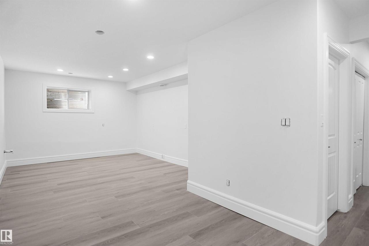Recessed lighting illuminates this space featuring wood-finish flooring, a window, and white trim throughout - 6823 18 Avenue Sw, Edmonton, AB - Indoor Photo Showing Other Room