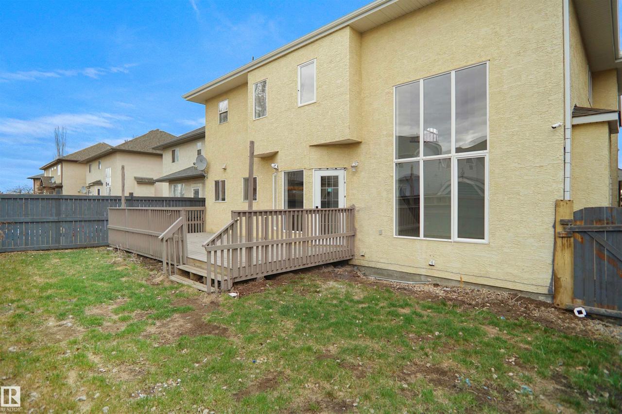 Private backyard space featuring a wood deck with railings, a rear entry door, and a large multi-pane window - 6823 18 Avenue Sw, Edmonton, AB - Outdoor With Exterior